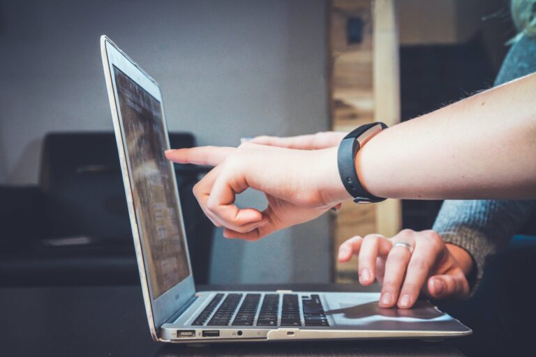 Two people working together and pointing at a laptop